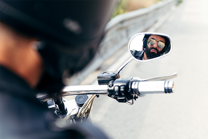 motorista reflejado en el retrovisor mientras conduce la moto