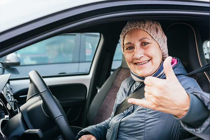 mujer mayor de 65 años feliz conduciendo coche